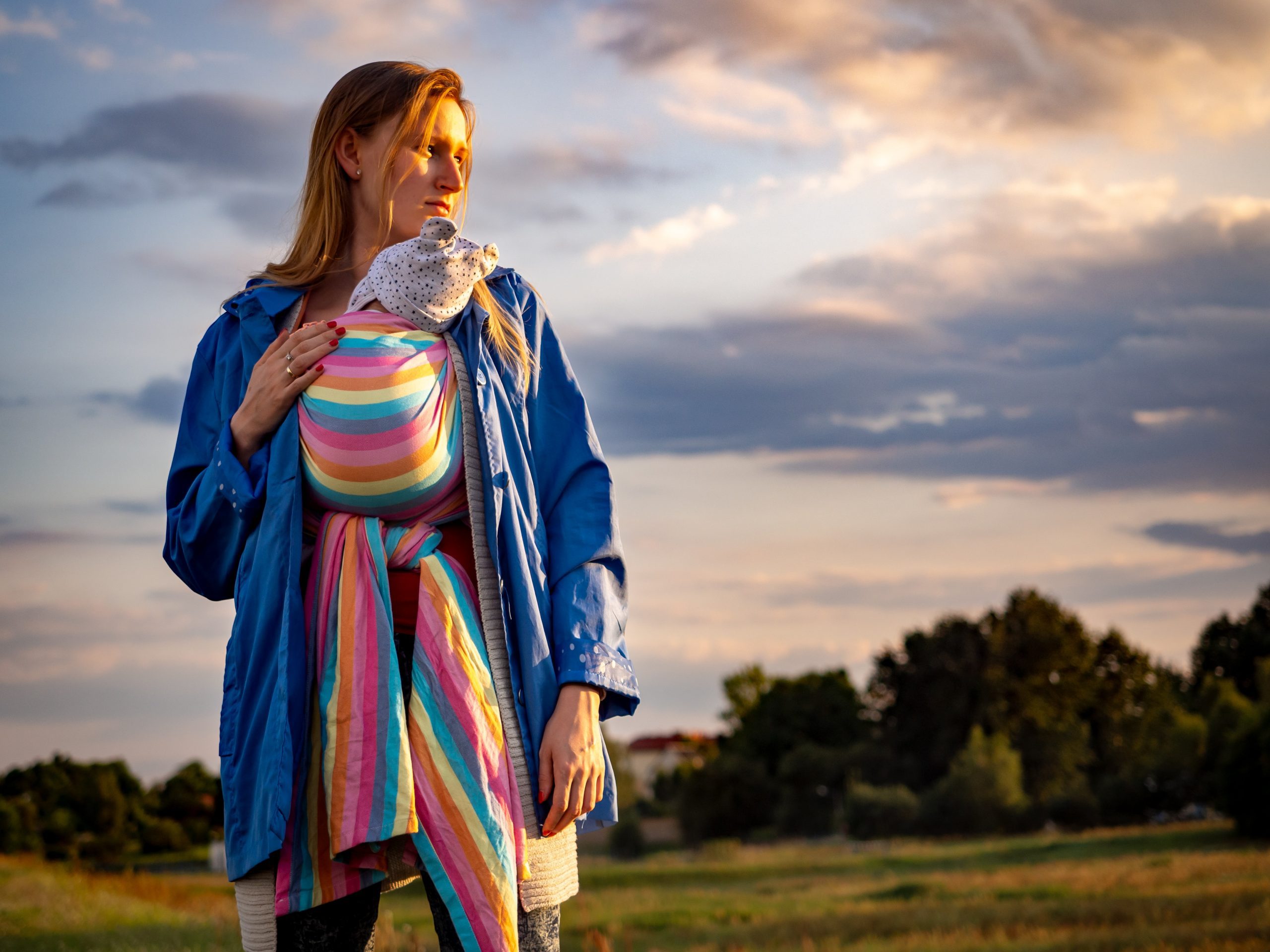 Picture of mother with baby in a rainbow wrap standing in a field