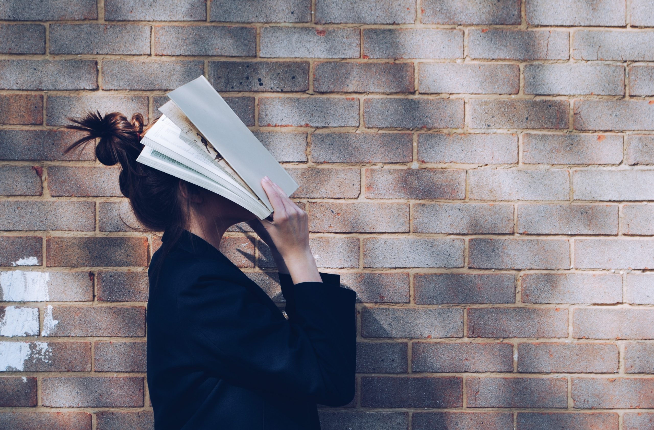 Person covering face with book