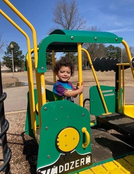 toddler playing on bulldozer playground structure