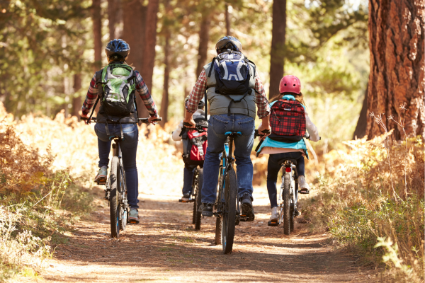 family movement riding bikes together through the woods