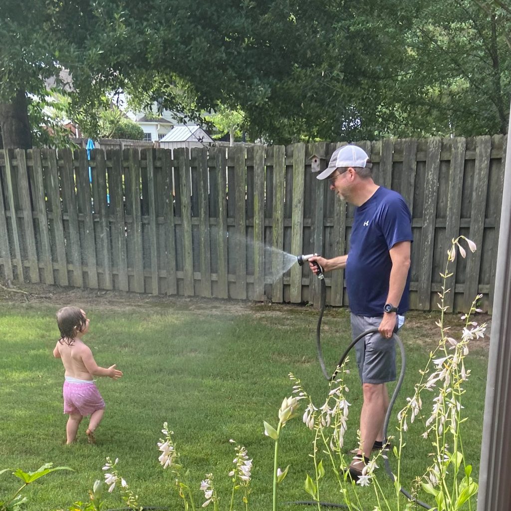 dad and baby playing in the hose