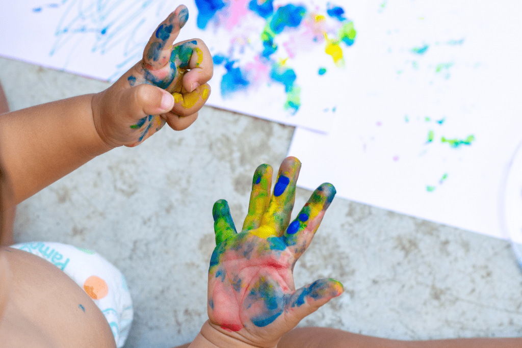 toddler with paint on their hands during a mommy and me playgroup
