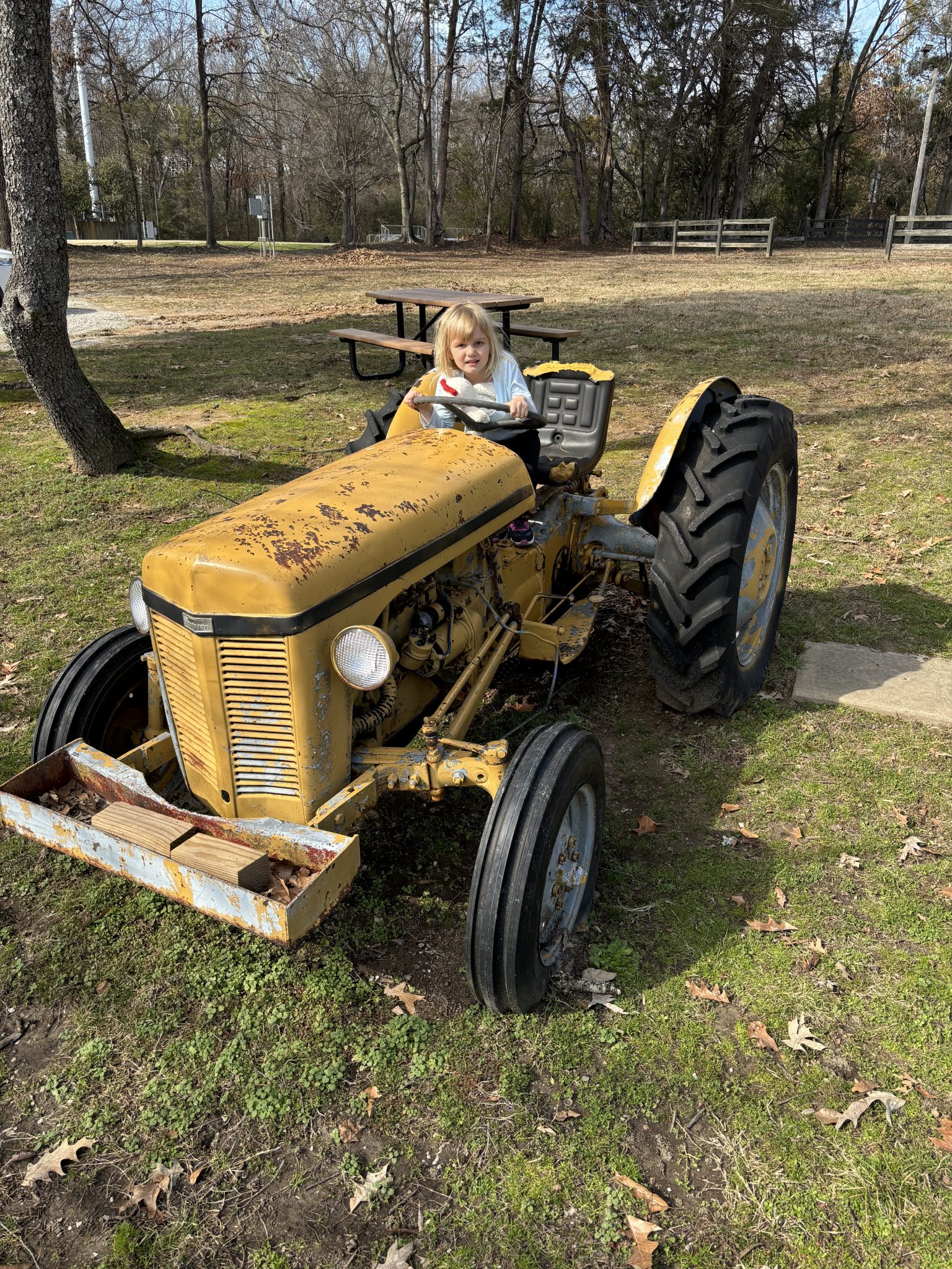 A kid sitting on a yellow tractor in Bobby Lanier Farm Park