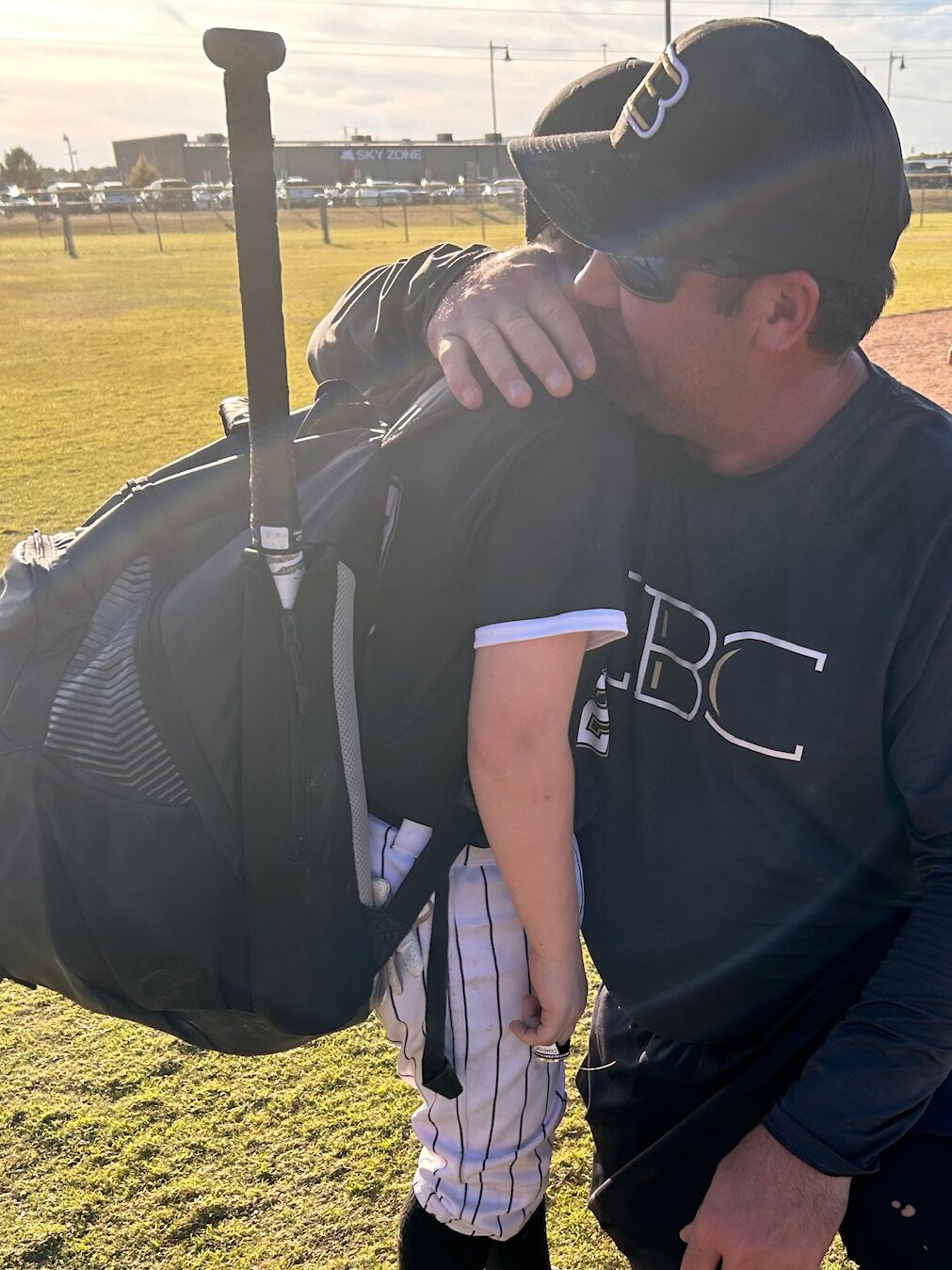 Father with son hugging on baseball field 