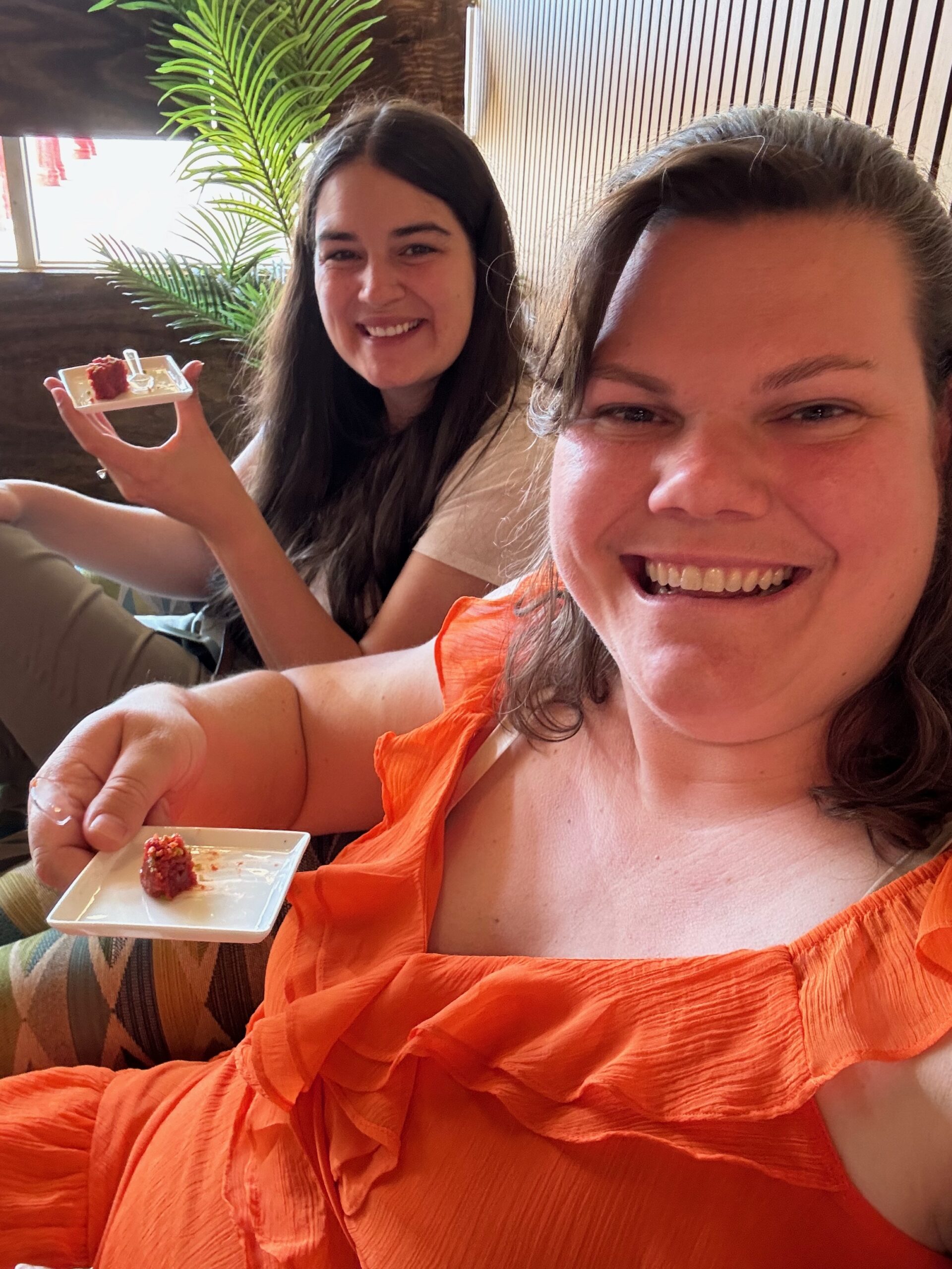 Two girls holding up two small red pastries 