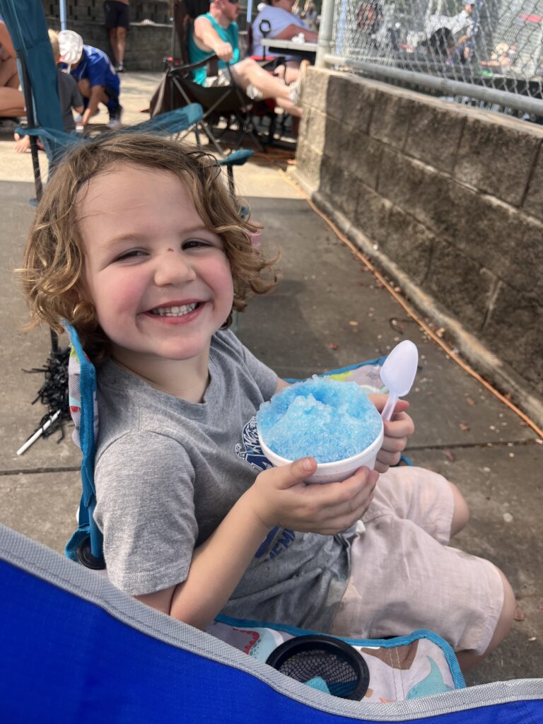 Son getting snow cone at baseball game 
