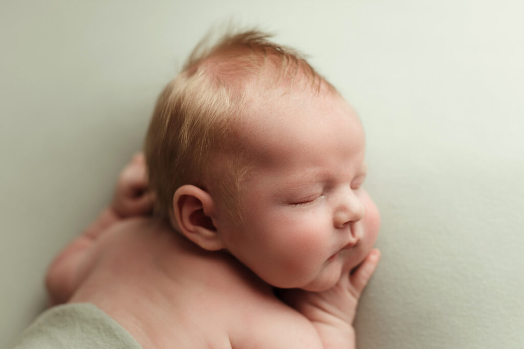 sleeping newborn baby on a light green blanket