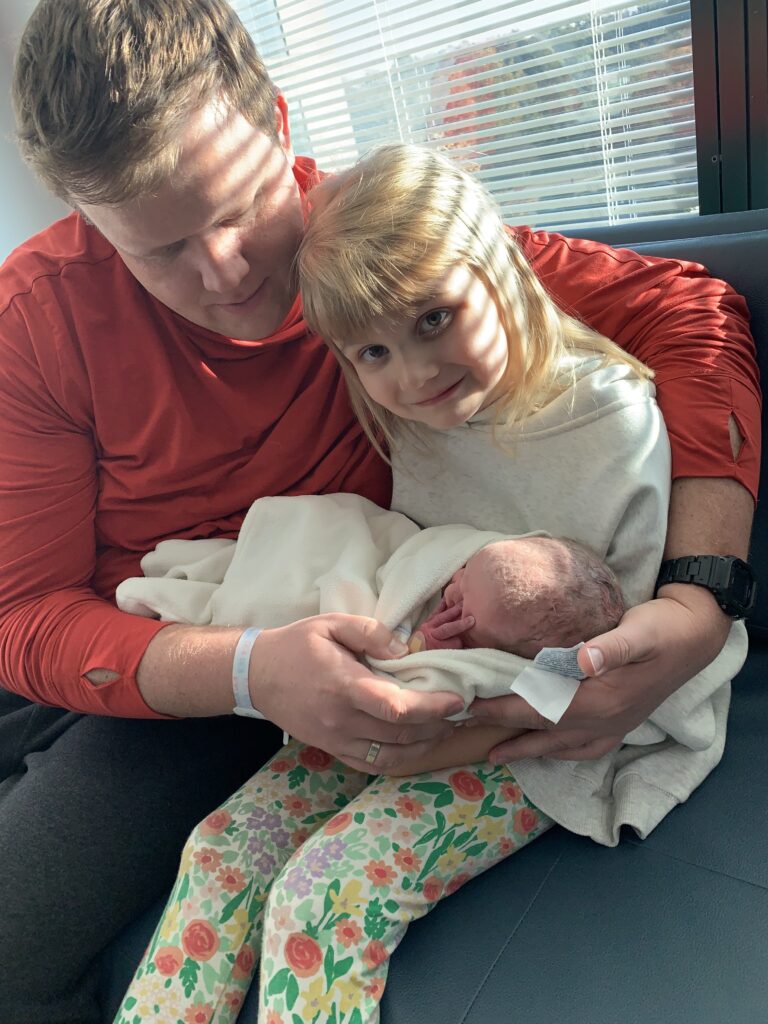 Man and girl holding a baby after preparing for baby sister 