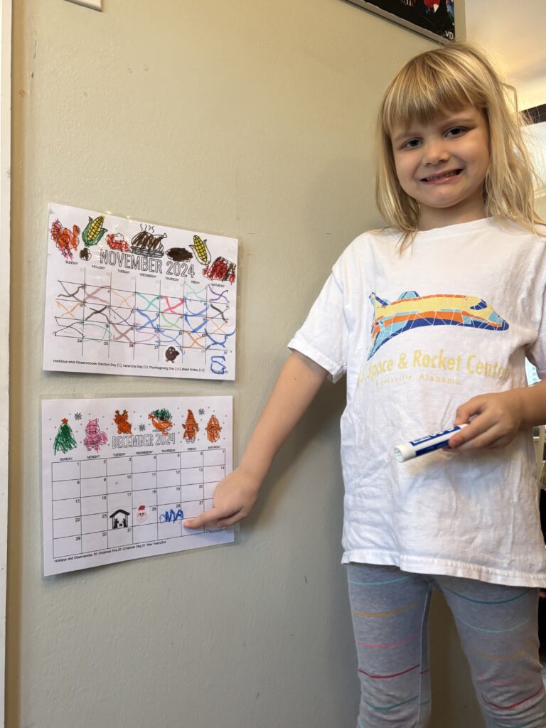 Little girl pointing to a December calendar.