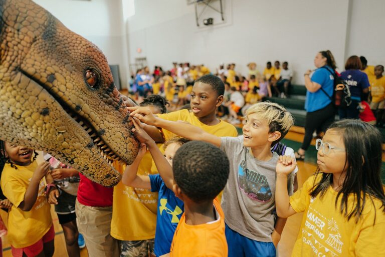 kids playing with a dinosaur at a YMCA camp