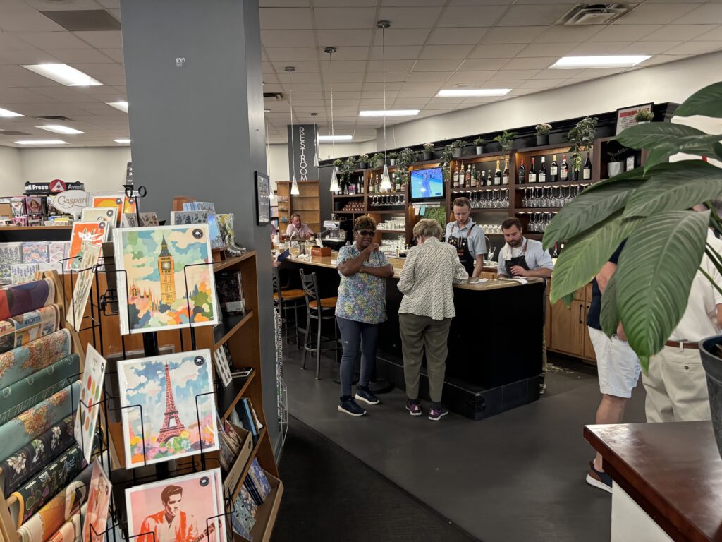 Two ladies chatting in front of a black bar with two servers behind the bar at Novel bookstore